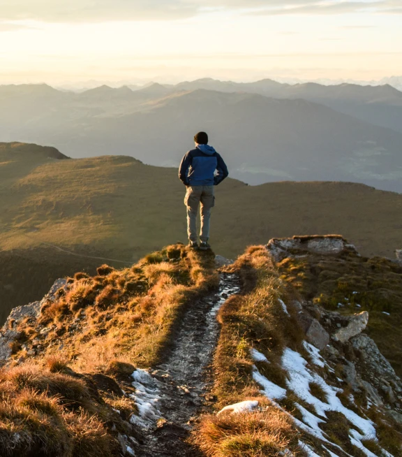 a man looks out at the view while hiking in the mountains